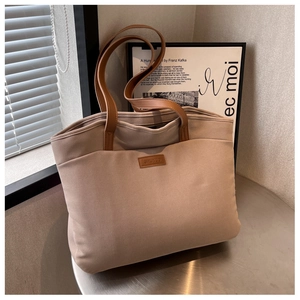 Detailed view of the SHUNUO leather logo label on a large two-tone canvas tote bag