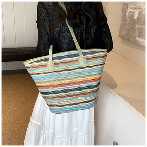 Detailed view of a large colorful striped straw tote bag showing shoulder strap fit