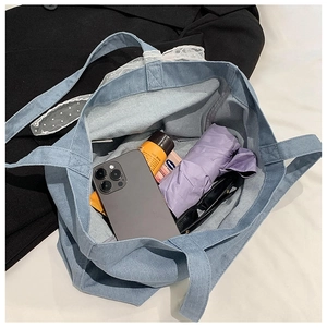 Top view of large light blue denim tote bag with lace detail and spacious interior