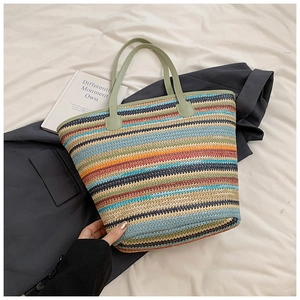 Close-up of multicolored striped woven tote bag with green leather handles on white fabric
