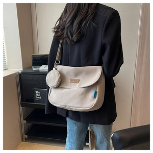 Beige canvas crossbody bag with small coin purse and wide shoulder strap shown on model