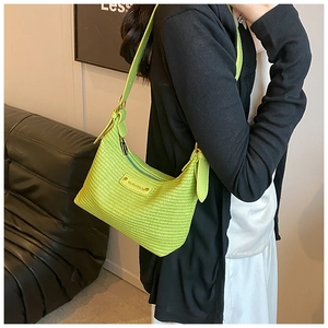 Détail du sac en paille tressée verte avec finitions dorées et bandoulière en cuir