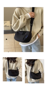 Close-up of minimalist black dumpling crossbody bag with adjustable wide fabric strap