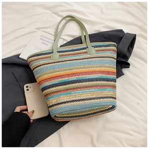 Detail of colorful striped straw tote bag with light green handles on a white sheet