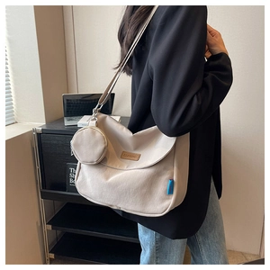 Detail of beige large canvas crossbody bag with round pouch and brand leather patch
