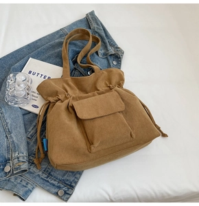 Detalle del bolso tote de pana color caqui con cierre de cordón y bolsillo frontal de solapa