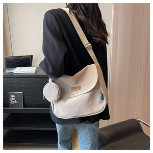 Detail of beige canvas messenger bag with adjustable strap and small round coin purse