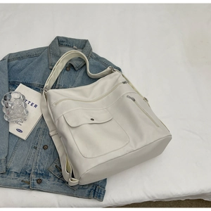 Dettaglio ravvicinato della borsa tote avorio multi-tasca con cerniere e patta magnetica