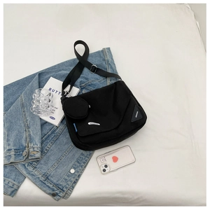 Détail du sac bandoulière en toile noire avec mini pochette et sangle réglable