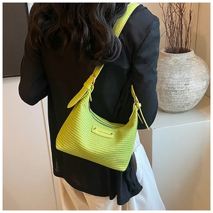 Détail du sac hobo vert néon avec texture tissée porté sur un blazer noir élégant