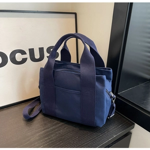 Detailed view of dark blue canvas tote showing wide handles and adjustable strap