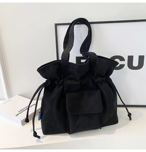 Detailed texture of black corduroy tote bag with drawstring closure and front flap pocket