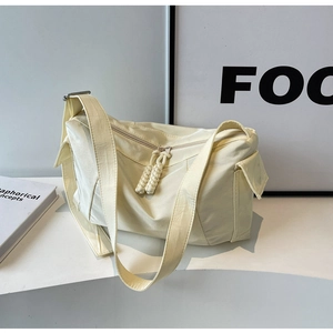 Dettaglio della borsa a tracolla in nylon crema con doppia zip e tasca laterale