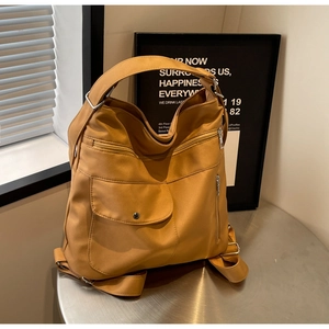 Dettaglio di un grande zaino in nylon giallo con tasca magnetica su un tavolo argentato