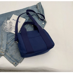 Detail of navy blue canvas tote bag with wide handles and adjustable strap on denim