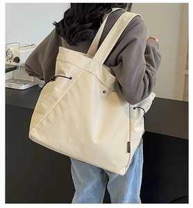 Detail view of cream canvas tote bag with side drawstrings and adjustable straps