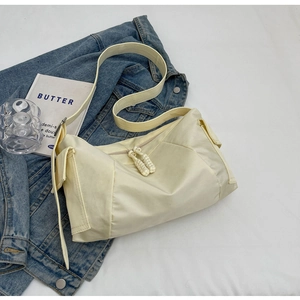 Dettaglio borsa tote in nylon crema con cerniere intrecciate su giacca denim