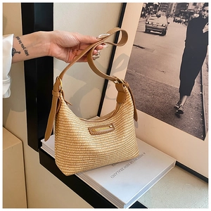 Détail du sac hobo en paille tressée beige avec bandoulière en cuir brun et boucle dorée