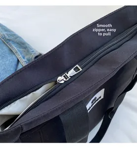 Detail view of the smooth silver zipper and durable black fabric handles on canvas tote