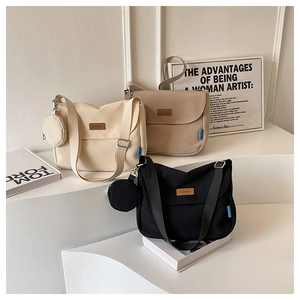 Detailed display of large canvas messenger bags in cream, khaki, and black colors