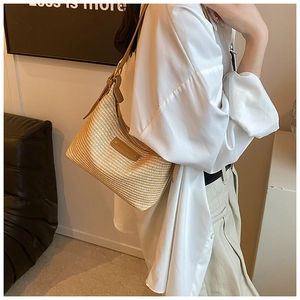 Détail du sac hobo en paille tressée avec garniture en cuir marron et boucles en métal