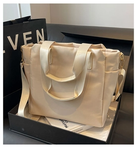 Detail view of beige nylon tote bag with golden hardware inside a black gift box