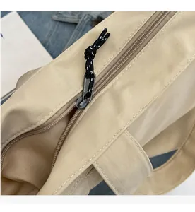 Detailed macro view of the smooth beige nylon tote bag zipper with a dual-color pull cord