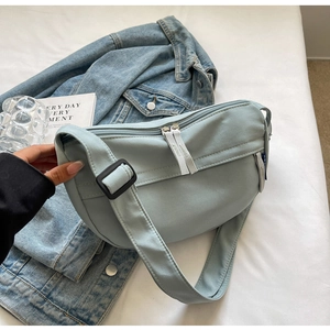 Detailed shot of light blue canvas crescent bag with dual zippers and adjustable strap