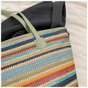 Close-up of colorful striped woven tote bag with durable green PU leather handles