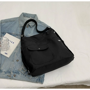 Dettaglio borsa a tracolla in nylon nero con tasche funzionali e chiusura a scatto