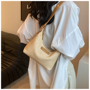 Gros plan du sac demi-lune en paille tressée avec bandoulière en cuir marron et plaque