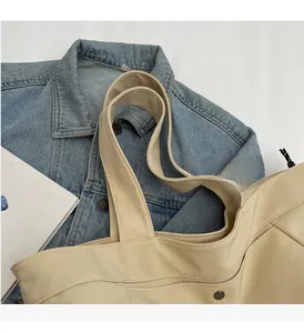 Close-up of wide handles and durable stitching on a cream nylon tote bag details