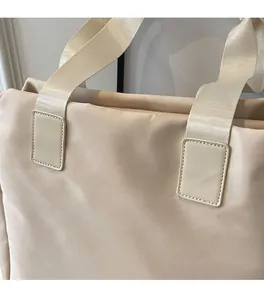 Detail of soft quilted texture and nylon strap on a cream minimalist tote bag