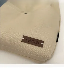 Detail of beige canvas bag showing leather patch and metal snap button closure