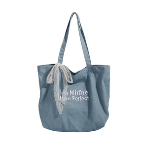 Blue denim tote bag with white embroidery and lace bow decoration for casual style