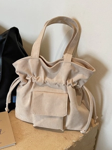 Bolso tote de pana beige con cierre de cordón y bolsillo sobre base de piedra