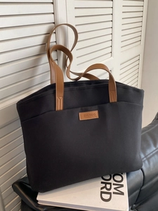 Minimalist black canvas tote bag with brown leather handles for daily commute