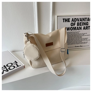 Detail of off-white canvas shoulder bag with brown leather logo tag and mini pouch