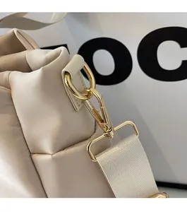 Detailed macro shot of premium golden D-ring hardware on a beige commuter tote bag