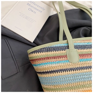 Detail of colorful striped woven tote bag with green leather straps and straw texture