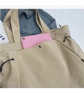 Detail of beige nylon tote bag interior showing capacity for a pink tablet and pocket
