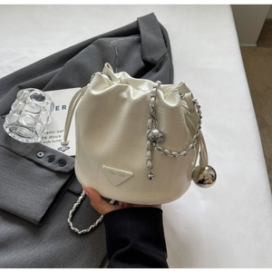 Detail of white bucket bag with drawstring closure and silver chain strap
