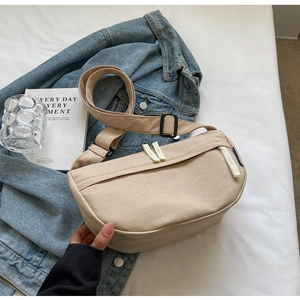 Detail of beige nylon crossbody bag featuring double zippers and black buckle strap
