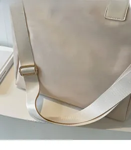 Detail view of the beige nylon tote bag with an adjustable wide shoulder strap and gold buckle