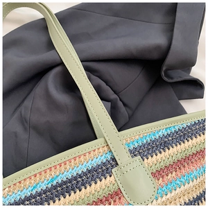 Detail of multi-color striped woven tote featuring leather strap and neat stitching