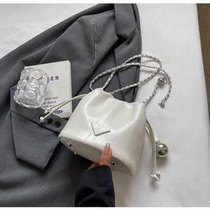 Macro view of white lizard-patterned bucket bag with silver chain and metal ball charm