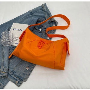 Dettaglio della borsa a tracolla in nylon arancione brillante su una giacca di jeans