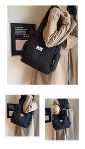 Detail of black canvas tote bag with fashion label and functional side zipper pocket