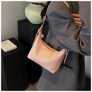 Détail du sac hobo en paille tressée rose avec bandoulière et ferrures dorées
