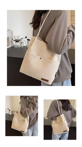 Close-up of beige canvas bucket bag with leather logo detail and shoulder strap in a cafe
